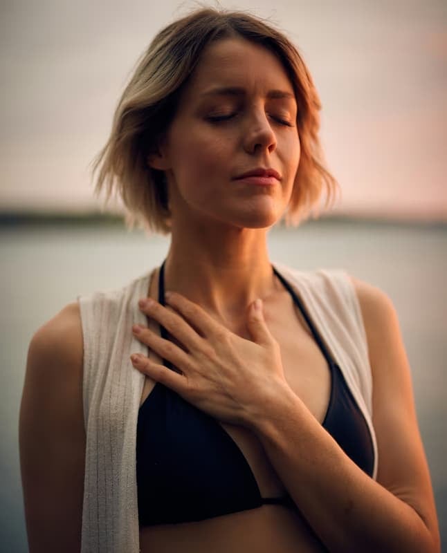 A woman with her hand on her chest, eyes closed